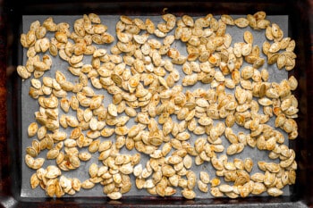 Roasted pumpkin seeds on a tray.