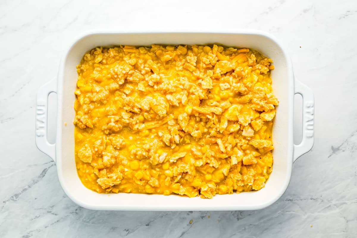 A white baking dish filled with scalloped corn topped with ritz crackers.