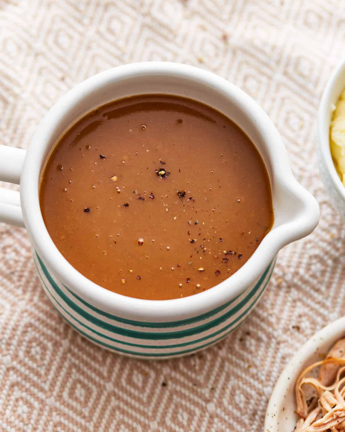 A bowl of make ahead turkey gravy on a table.