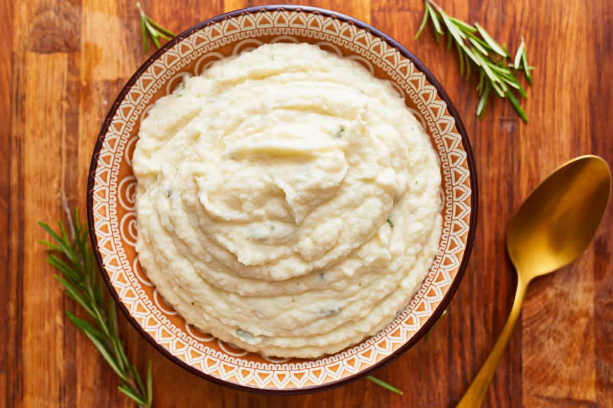 A bowl of garlic mashed cauliflower on a table.