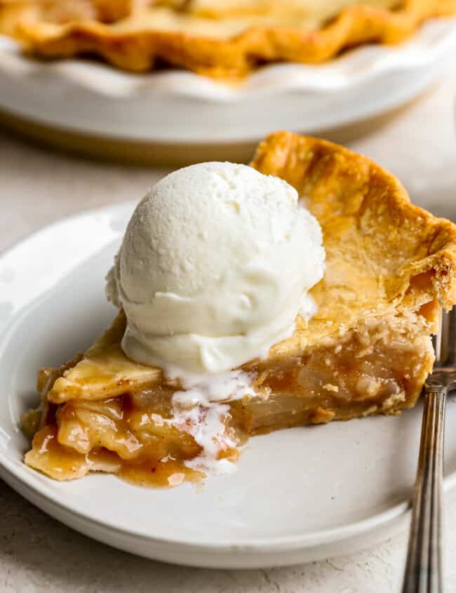 A slice of apple pie with ice cream on a plate.