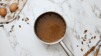 A Classic Pecan Pie with brown sauce and eggs on a marble countertop.