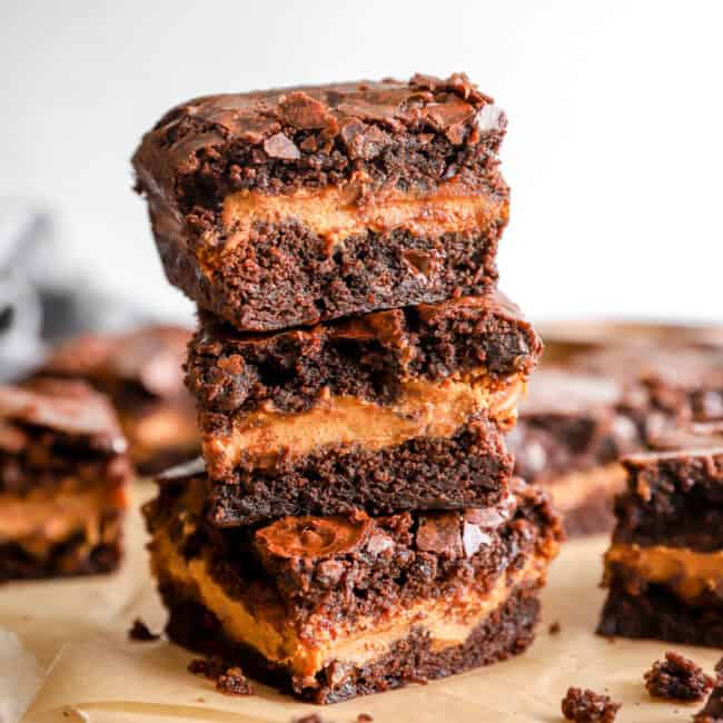 3 pumpkin brownies stacked on a cutting board.