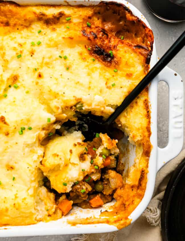 A dish of shepherd's pie with a spoon in it.