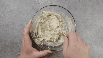 stirring herb butter in a glass bowl.