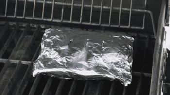 a smoking foil packet of wood chips on a grill.