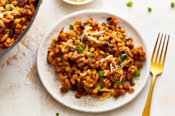 A plate of taco macaroni and cheese on a table next to a fork.