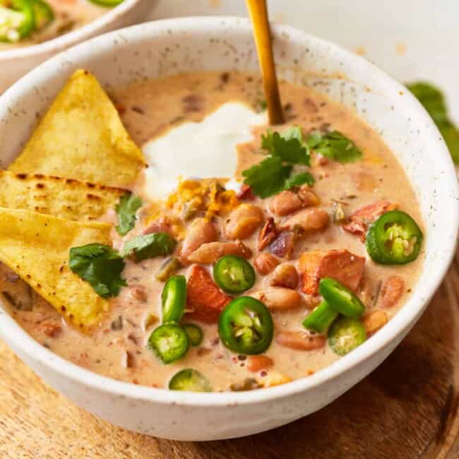 Two bowls of chili with tortilla chips and jalapenos.