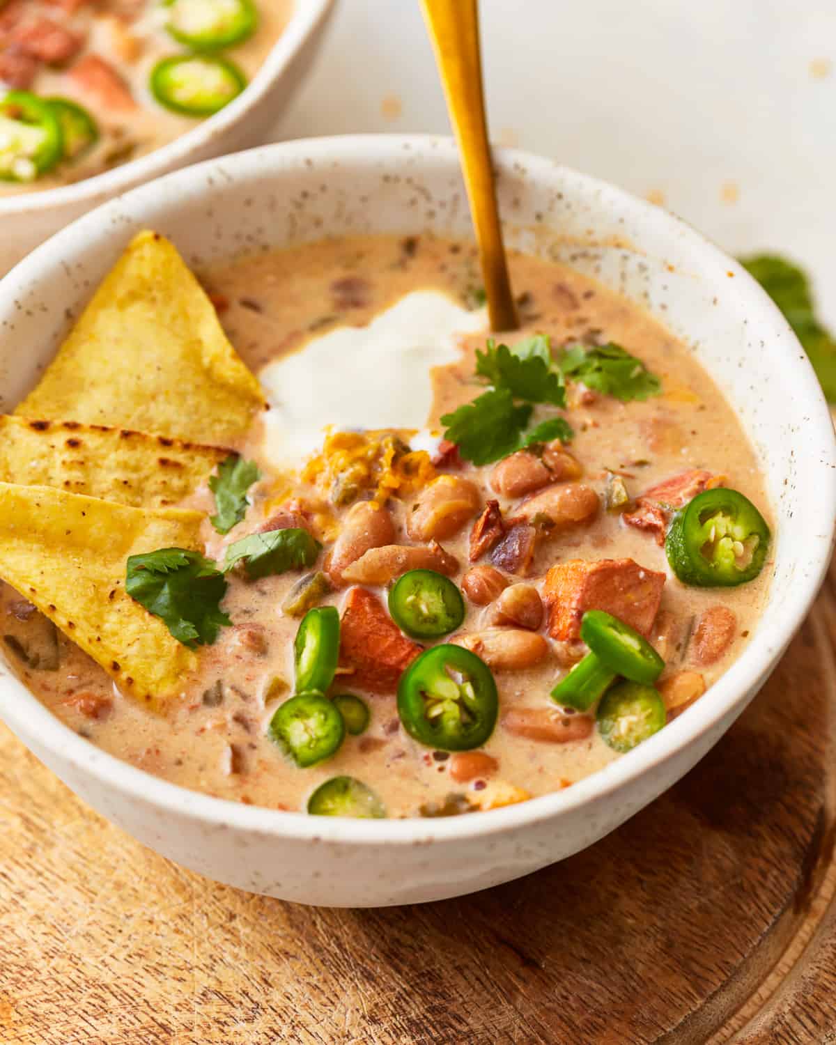 Two bowls of chili with tortilla chips and jalapenos.