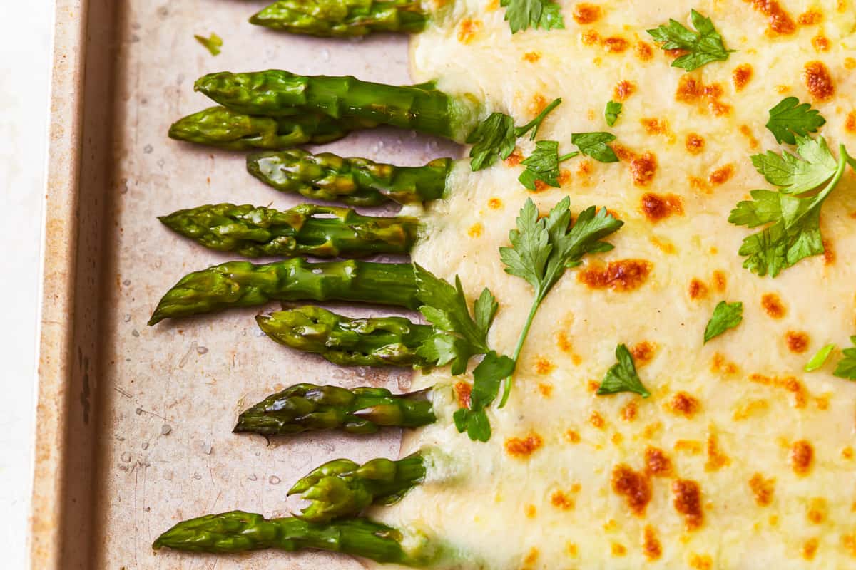 Cheesy asparagus on a baking tray.