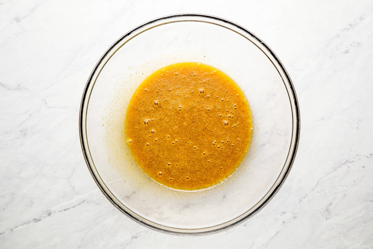 Wet ingredients in a glass bowl on a marble surface.