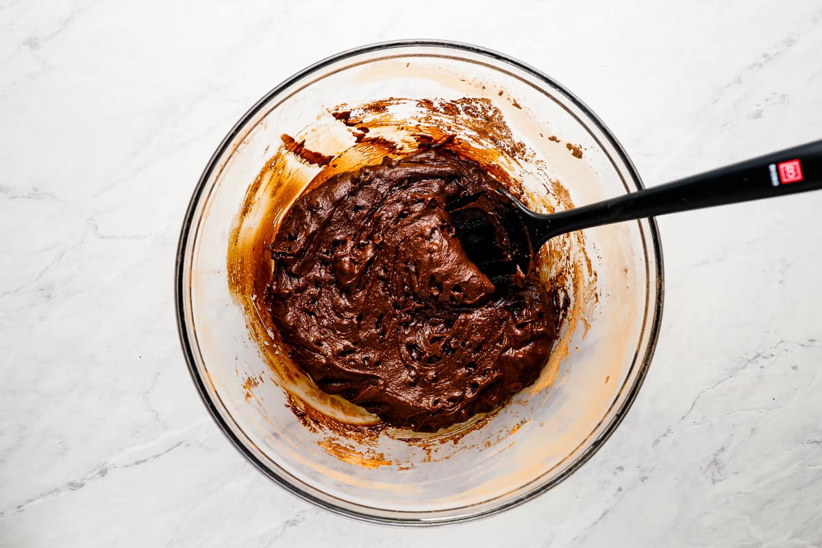 Chocolate cookie dough in a bowl with a spatula.