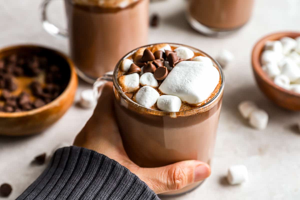 A person holding a cup of Crockpot hot chocolate with marshmallows.