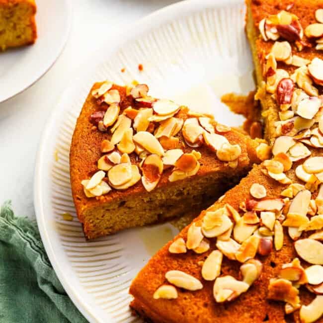 A slice of cake on a plate with almonds on it.