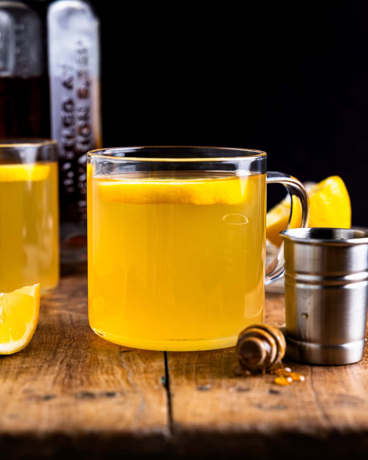 A cup of lemonade with honey and lemon slices on a wooden table.