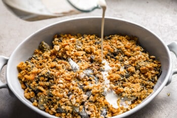 A bowl of greens and cheese being poured into a bowl.