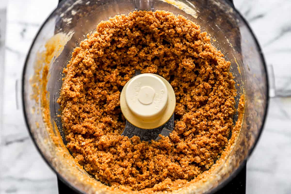 A food processor filled with brown crushed cookies.