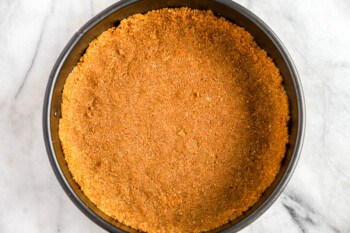 A pie crust in a black pan on a marble table.