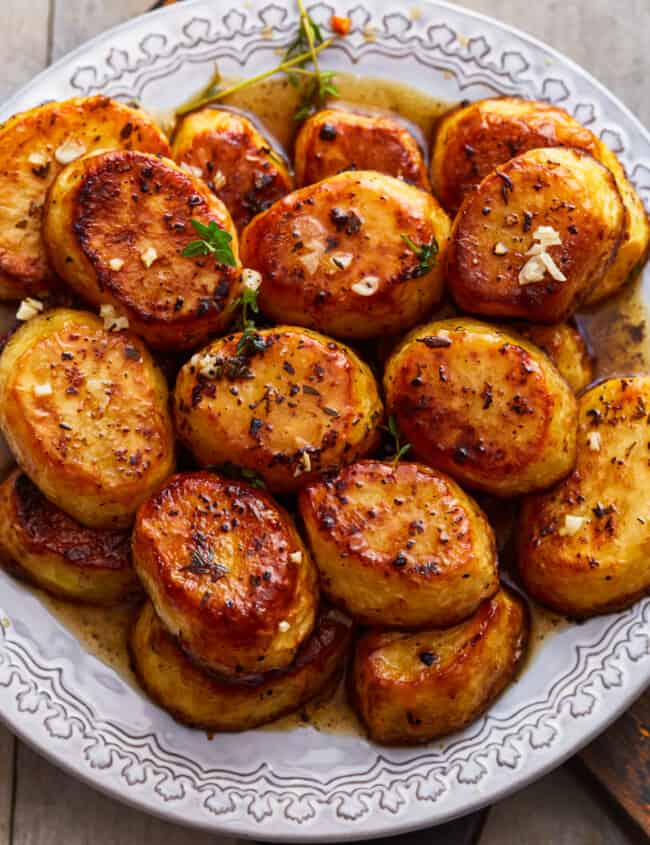 A plate of roasted potatoes on a wooden table.