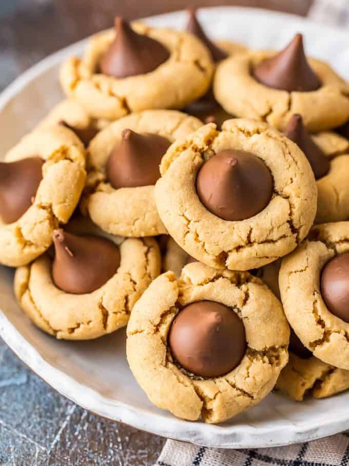 Peanut Butter Blossoms are a classic cookie recipe that is easy to make and loved by all! This BEST Peanut Butter Kiss Cookies Recipe has been in our family for years. Chocolate Peanut Butter Cookies are perfect for Christmas baking, but also made for enjoying year round, especially at Summer BBQs. When it comes to favorite cookie recipes, these Peanut Butter Hershey Kiss Cookies can't be beat. 