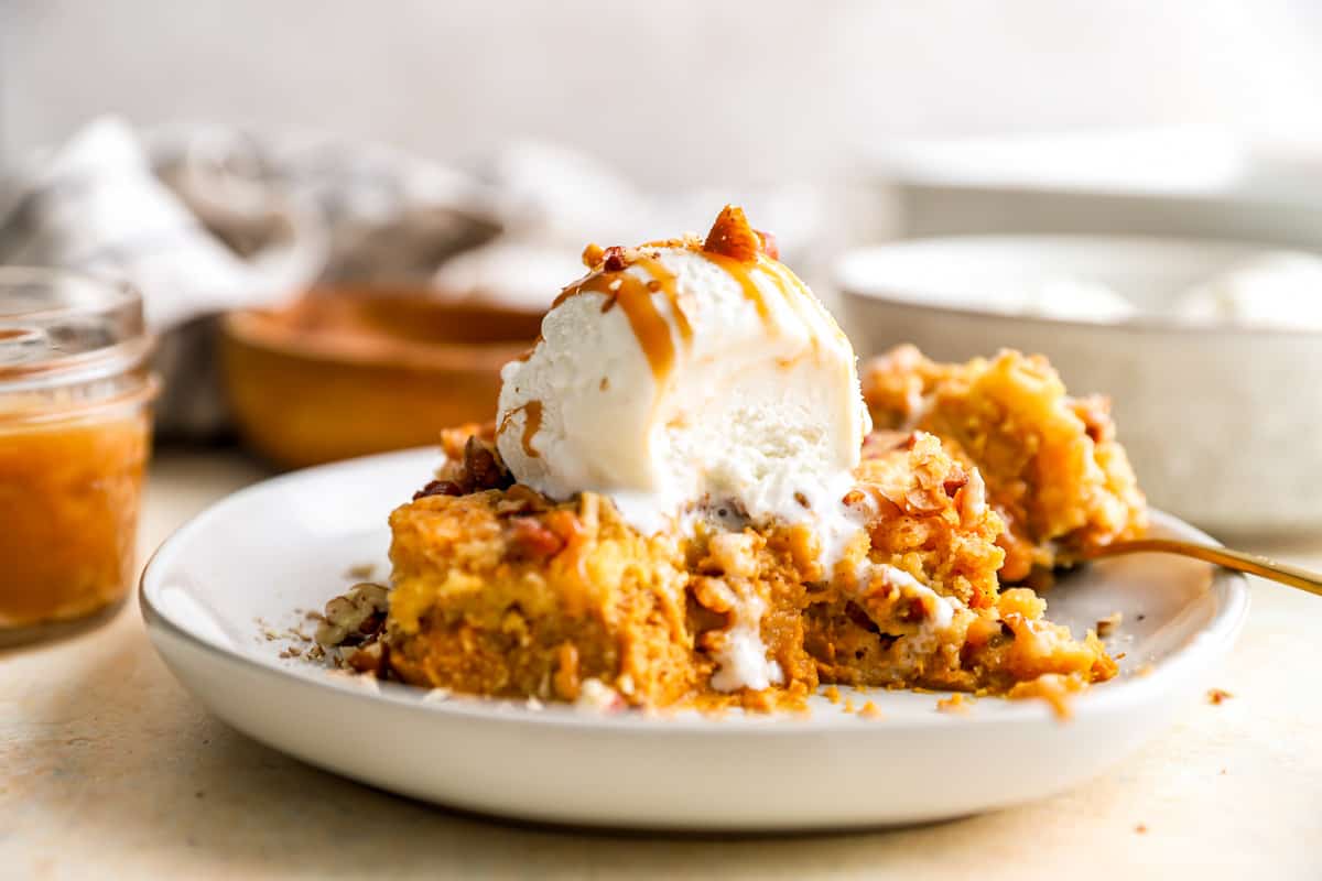 A partially-eaten piece of pumpkin pie dump cake on a plate.