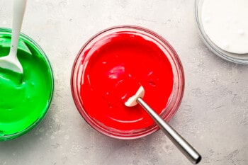 Three bowls of red, green, and white icing.