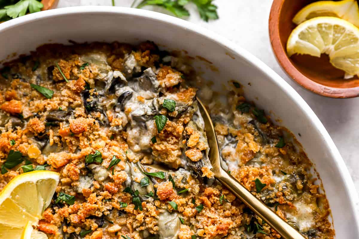 A dish of spinach and feta casserole with lemon wedges.