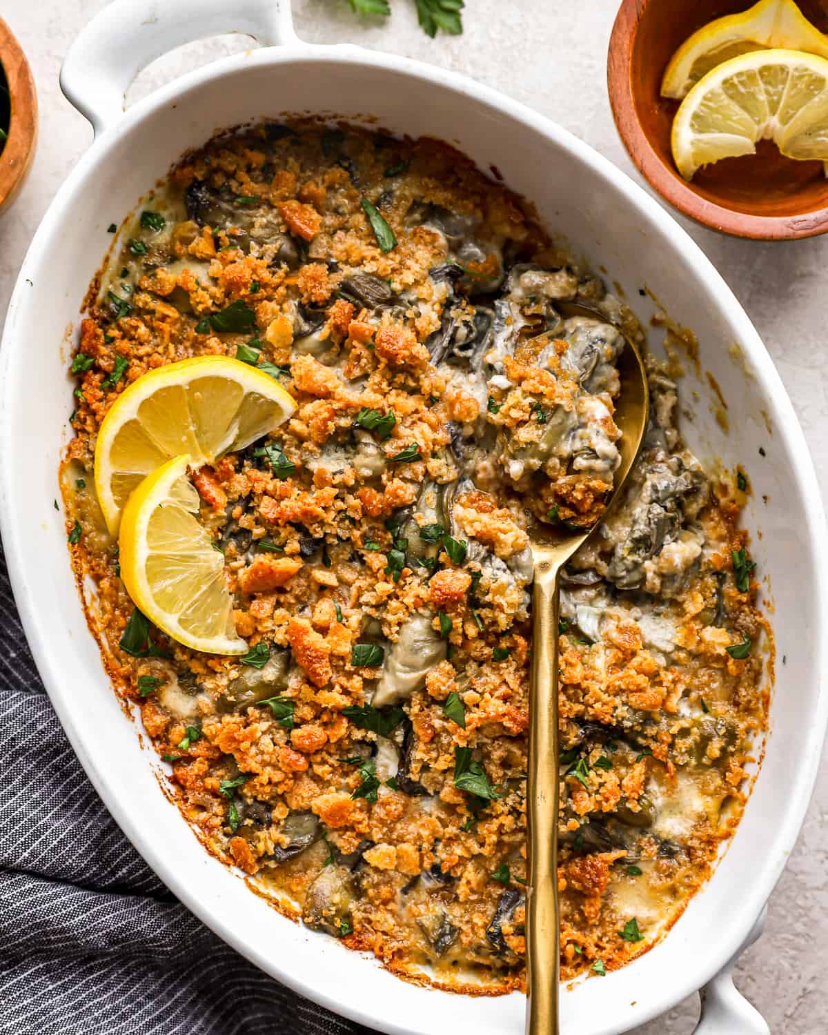 Scalloped oysters in a casserole dish with a serving spoon.