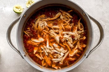 shredded chicken added to tomato broth in a dutch oven.