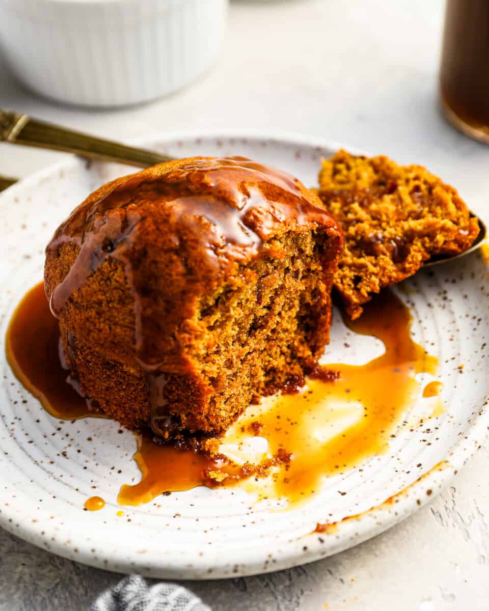 partially eaten sticky toffee pudding on a white plate.