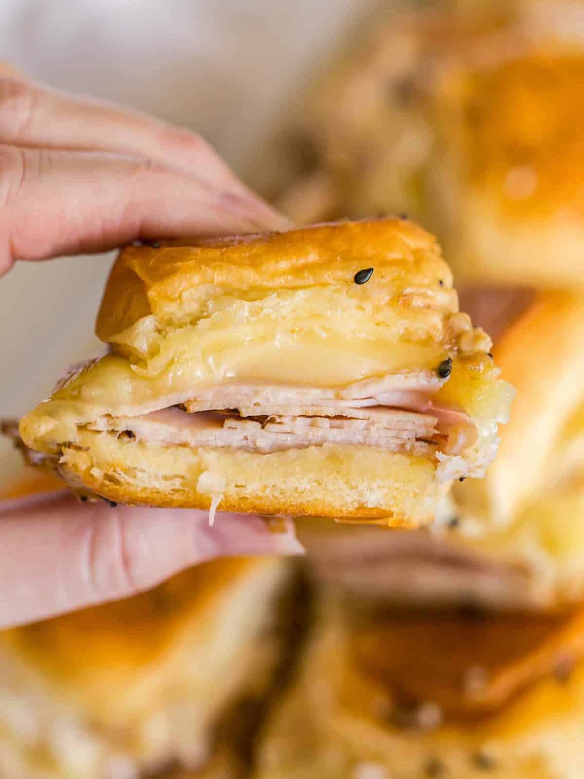 A hand holding up turkey slider.