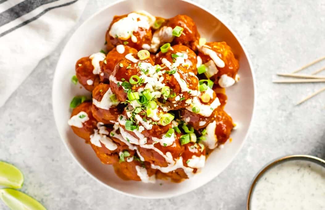 overhead picture of buffalo chicken meatballs garnished with ranch and scallions