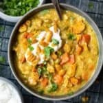 overhead view of a serving of mulligatawny soup in a gray bowl with a spoon.