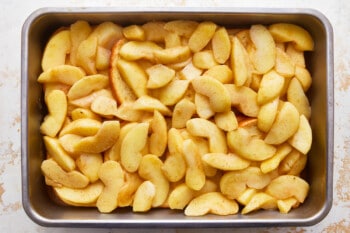 Sliced apples in a metal pan on a white background.