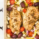 partial overhead view of baked greek chicken in a rectangular baking pan.