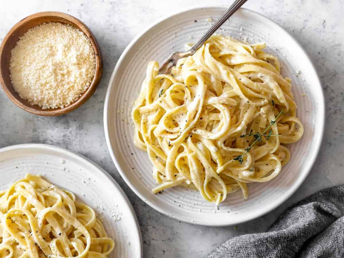 overhead view of a serving of fettuccini alfredo on a white plate with a fork.