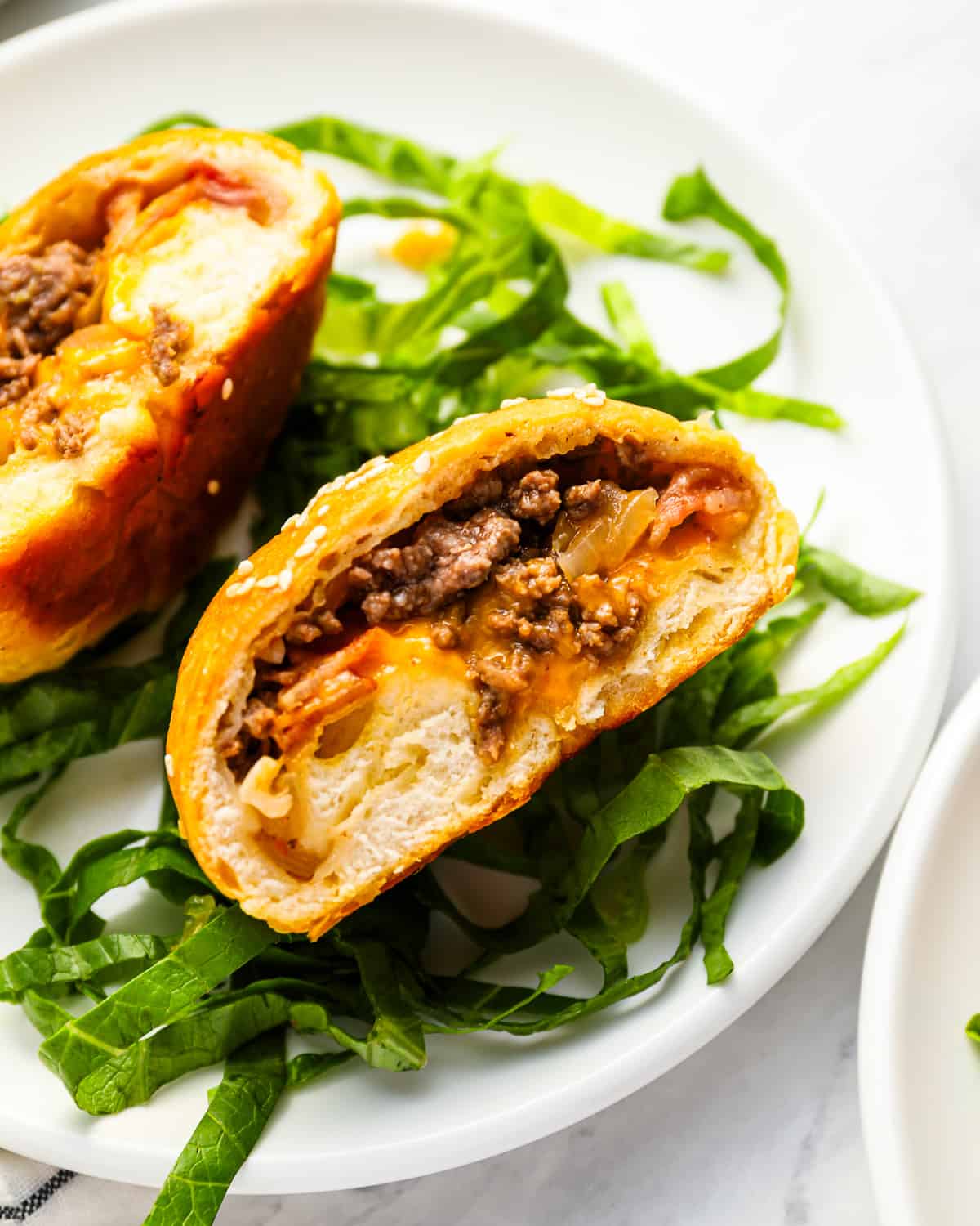 A cheeseburger bomb cut in half, to reveal ground beef, cheese, and ingredients inside.