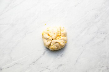 A cheeseburger bomb dough ball on a marble surface.