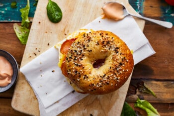 A bagel breakfast sandwich on a wooden cutting board.