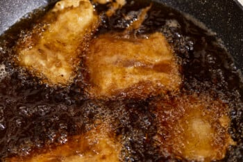 A frying pan with beer battered fish in it.