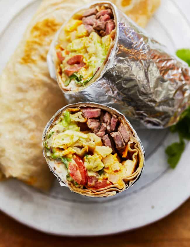 Two california burritos sitting on a plate.