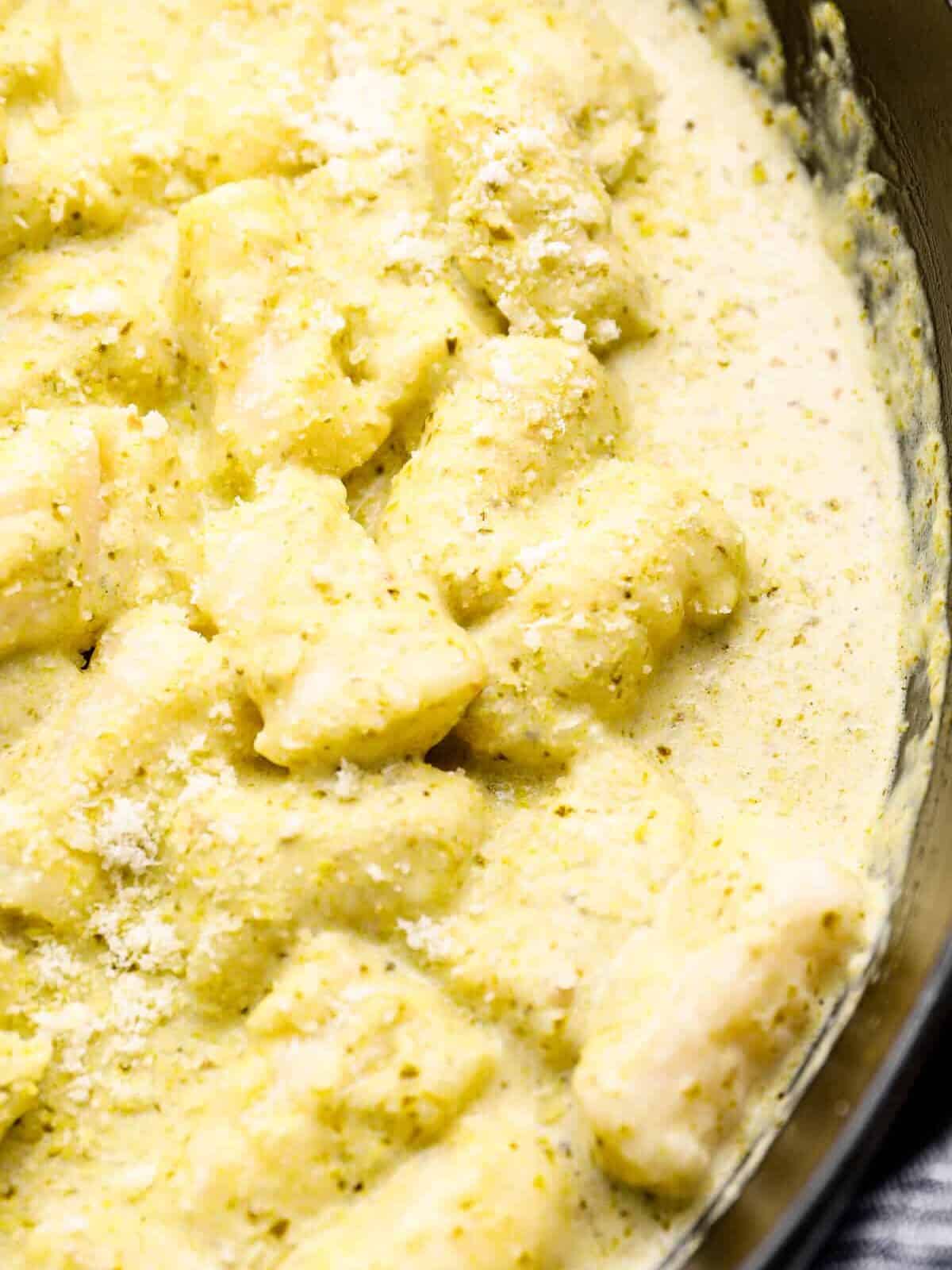 close up of gnocchi in pesto cream sauce.