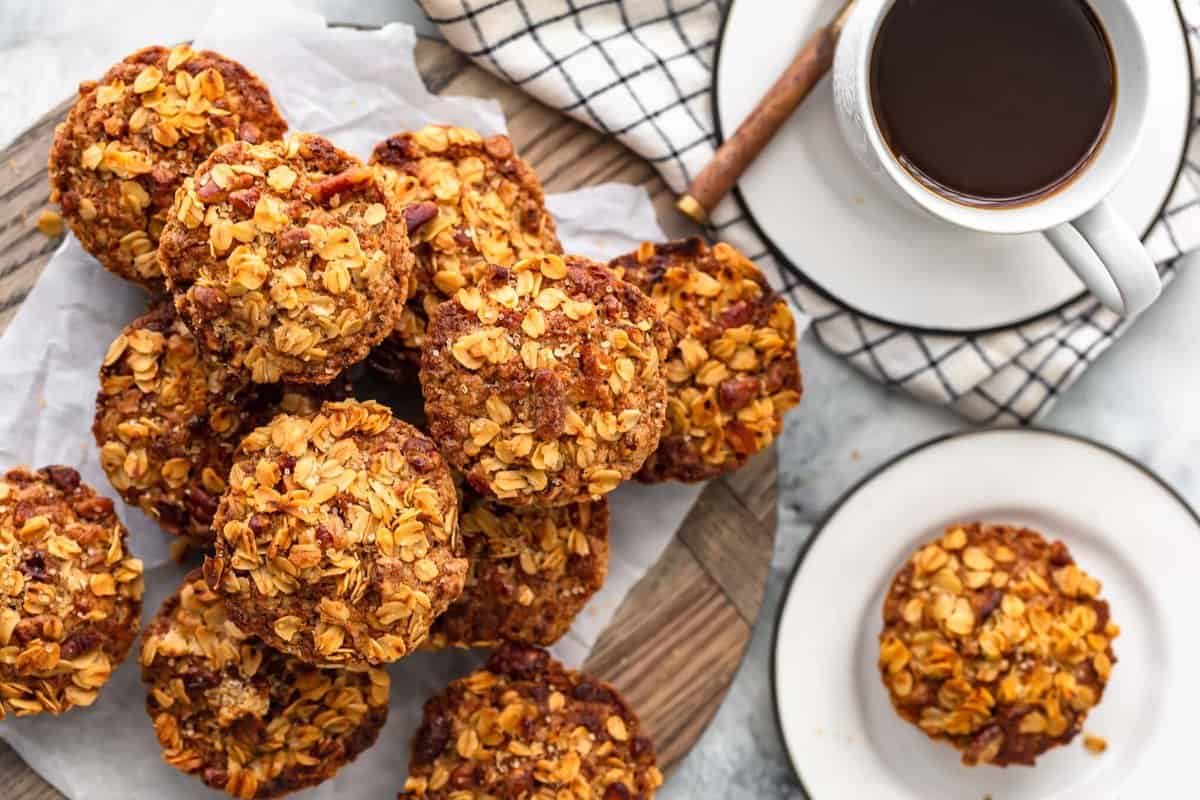 breakfast muffins stacked up on a wooden board, next to a cup of coffee 