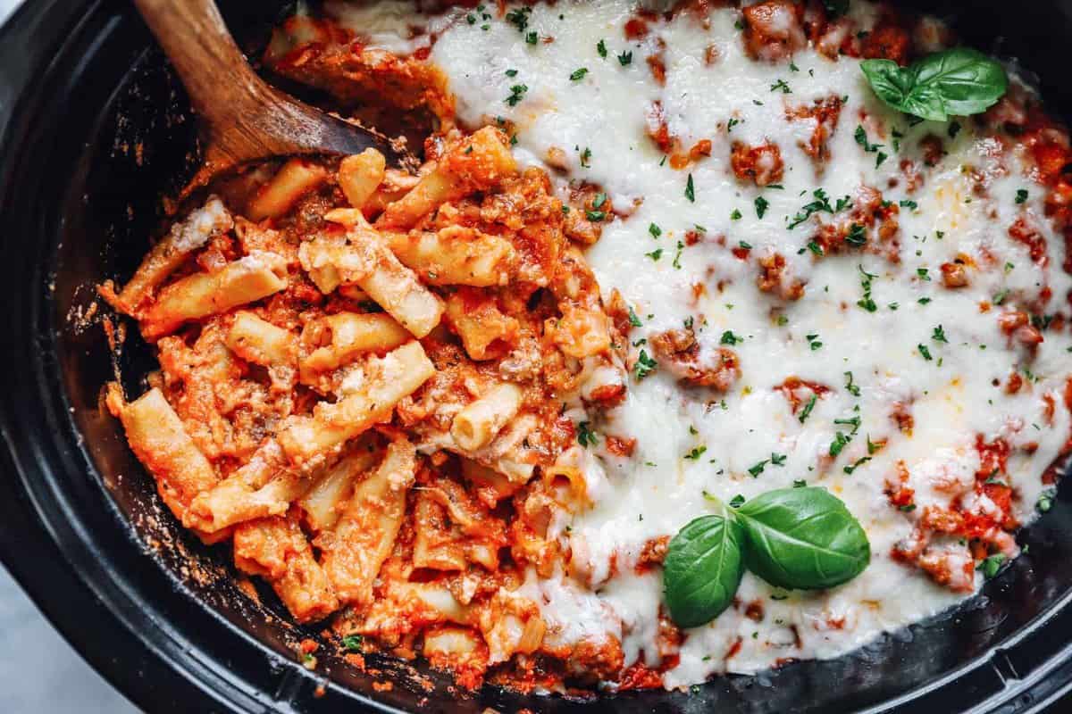 crockpot baked ziti in a crockpot with a wooden spoon.