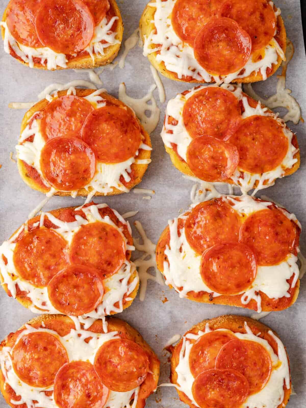 overhead view of 8 slices of garlic bread pizza with pepperonis on parchment paper.