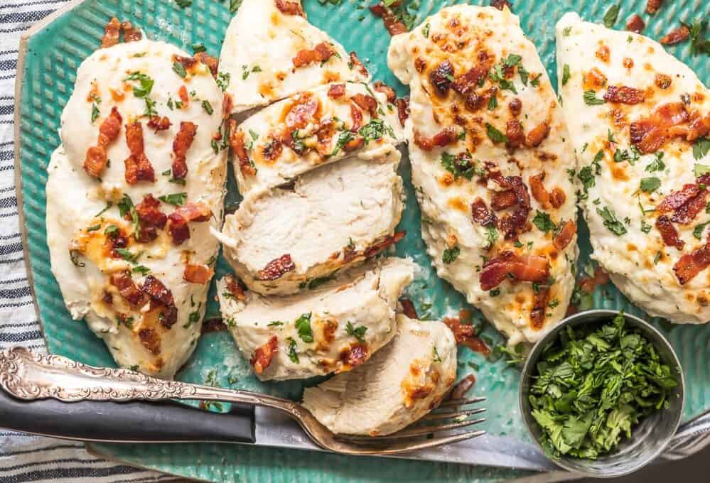 a plate of chicken breast baked in ranch dressing and topped with bacon crumbles