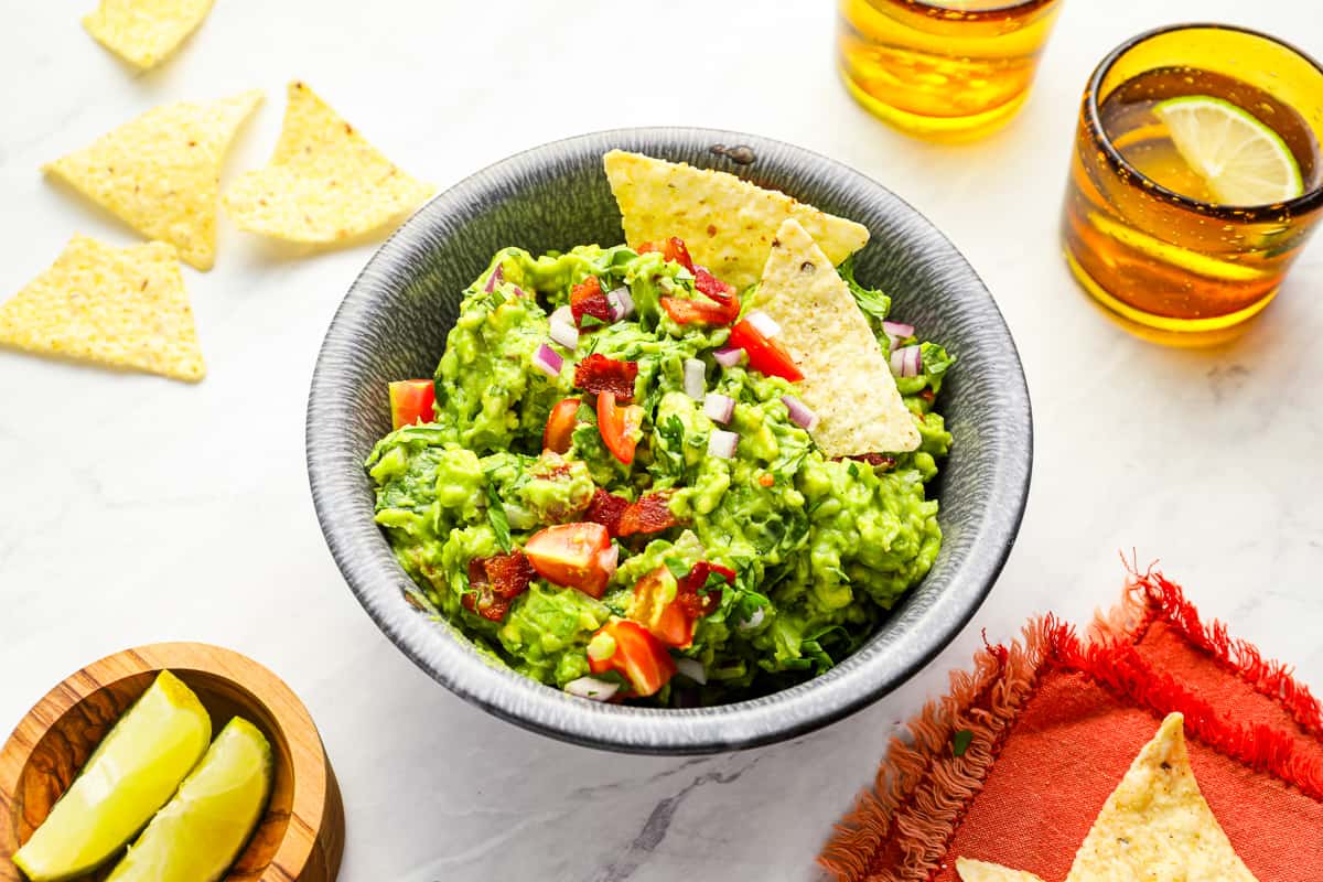 three-quarters view of blt guacamole in a bowl with tortilla chips.