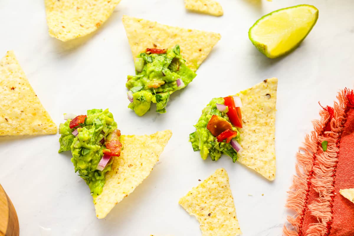 overhead view of chips with scoops of blt guacamole on them.