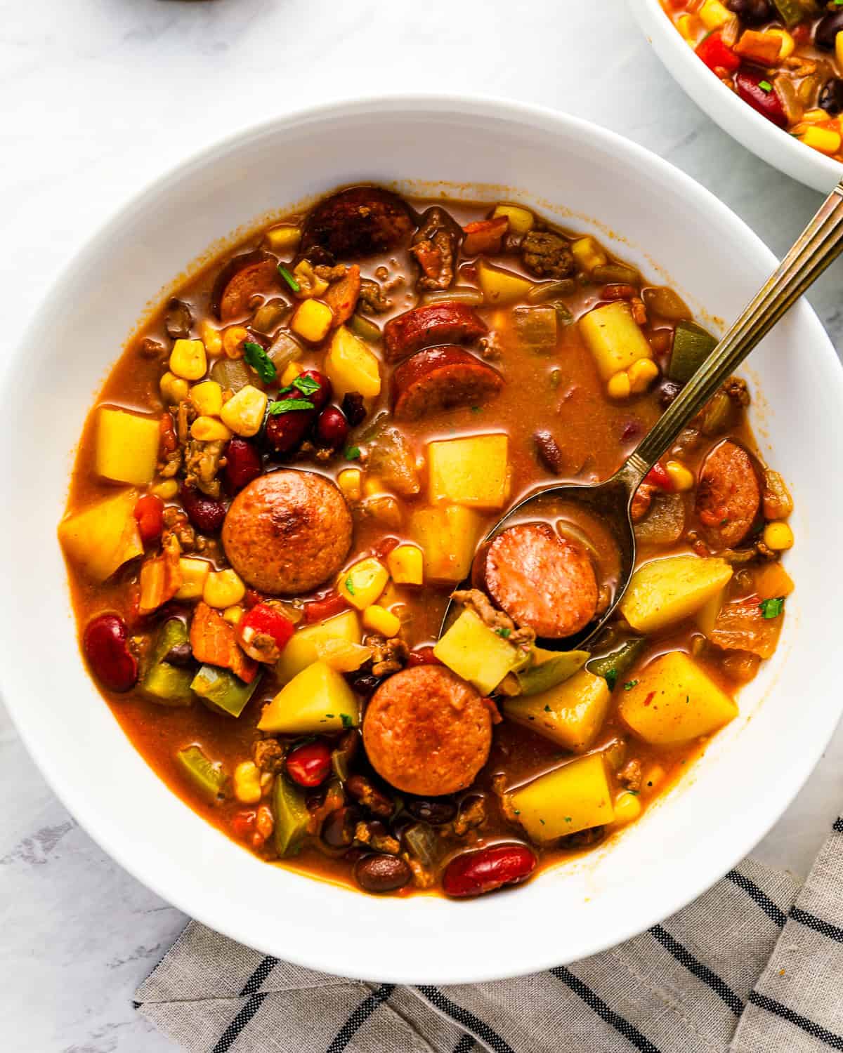 overhead view of a serving of cowboy stew in a white bowl with a spoon.