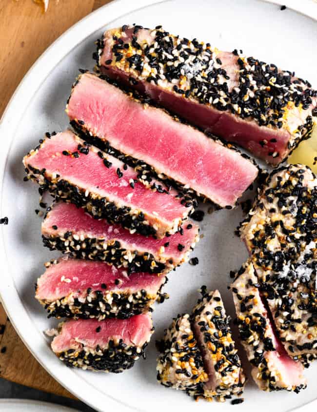 a plate of seared ahi tuna, covered in sesame seeds.